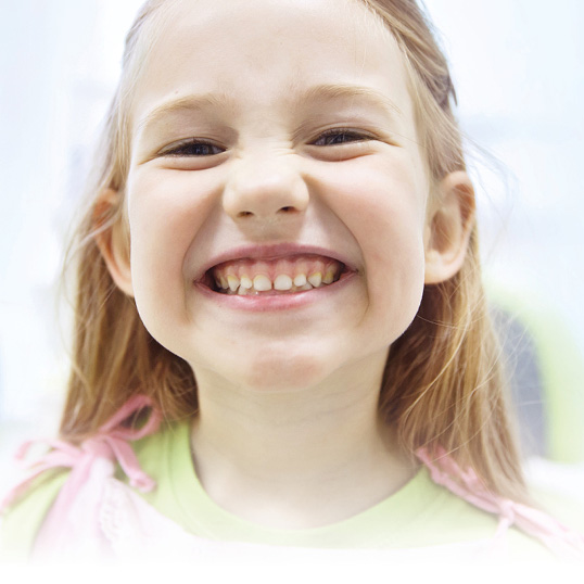 Fröhliches Kind zeigt seine Zähne - Kinder-Zahnheilkunde